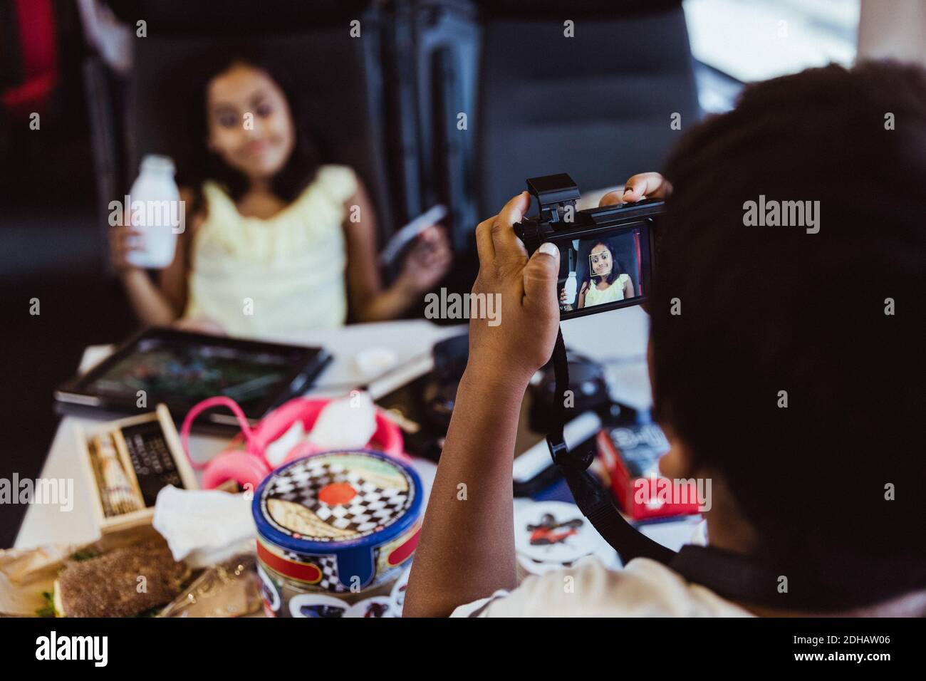 Garçon photographiant sa sœur à l'aide d'un appareil photo tout en voyageant en train Banque D'Images