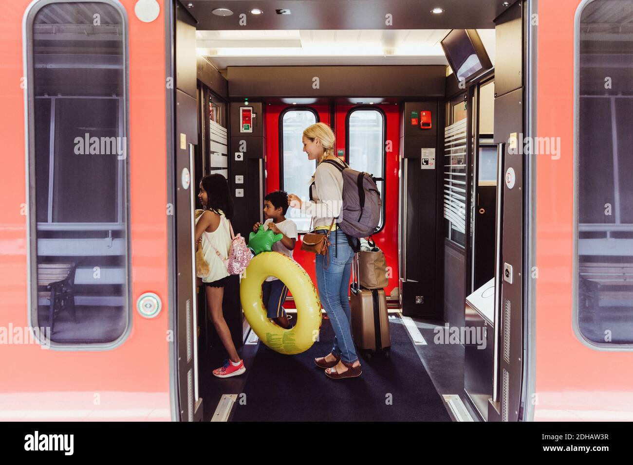 Mère et enfants avec bagages marchant dans le train à la gare Banque D'Images