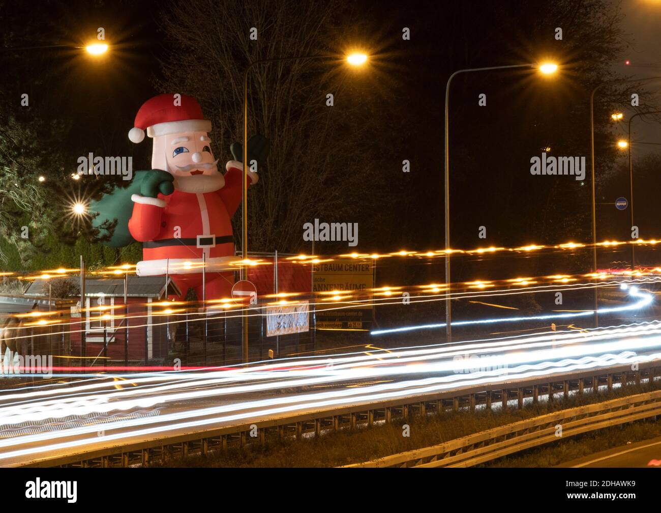 10 décembre 2020, Hessen, Francfort-sur-le-main : les pistes lumineuses des voitures de passage se distinguent devant un père Noël géant avec lequel un vendeur d'arbres de Noël annonce son activité. Pendant ce temps, les politiciens fédéraux discutent de relâcher les règles de verrouillage pour Noël. (Exposition longue durée) photo : Boris Roessler/dpa Banque D'Images