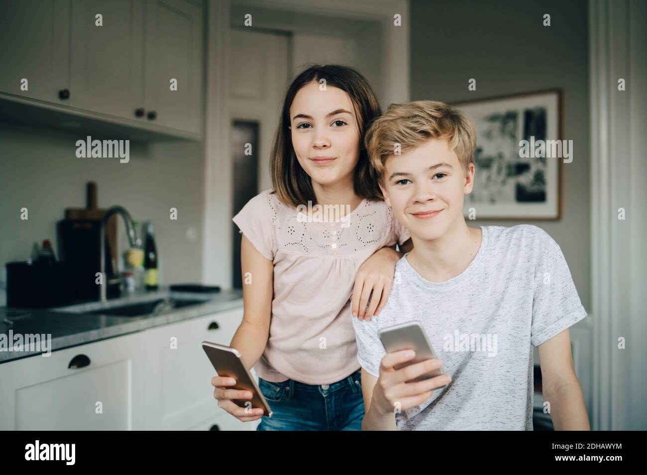 Portrait d'amis hommes et femmes souriants tenant un smartphone à la maison Banque D'Images