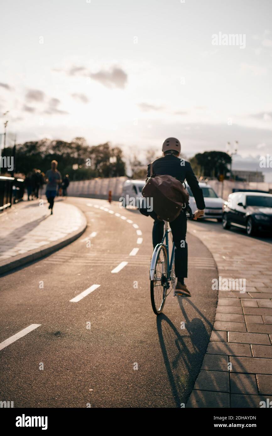 Vue arrière de l'homme d'affaires à vélo dans la rue dans la ville pendant jour ensoleillé Banque D'Images