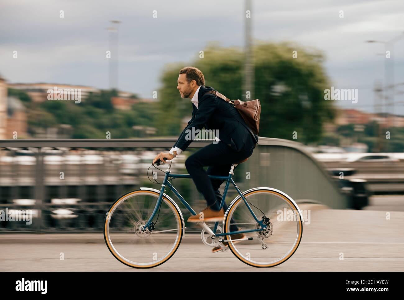 Vue latérale d'un homme d'affaires confiant à vélo dans la rue en ville Banque D'Images