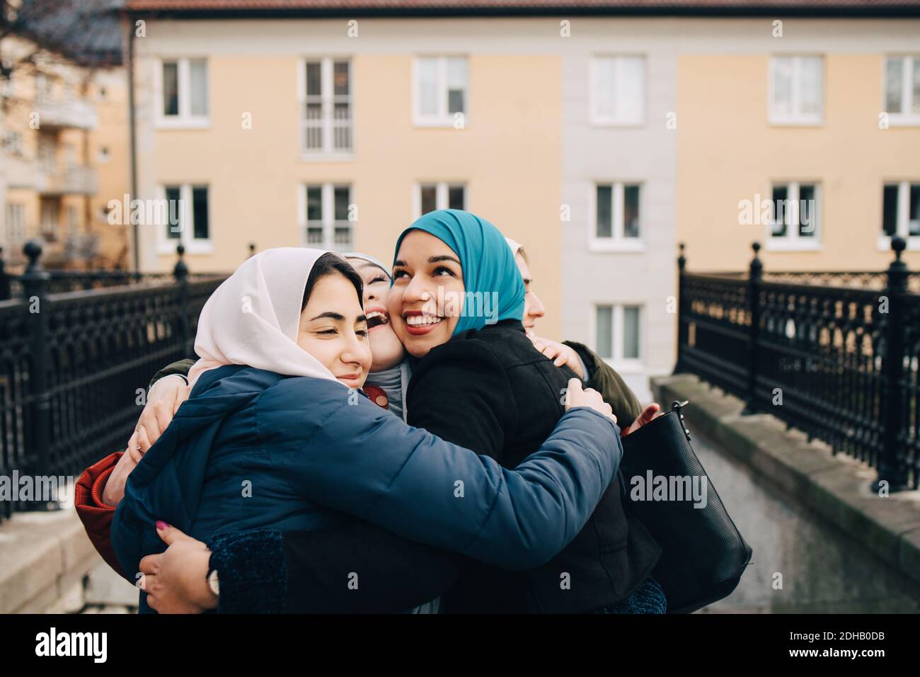 Des amies musulmanes multiethniques gaies s'embrassant en ville Banque D'Images