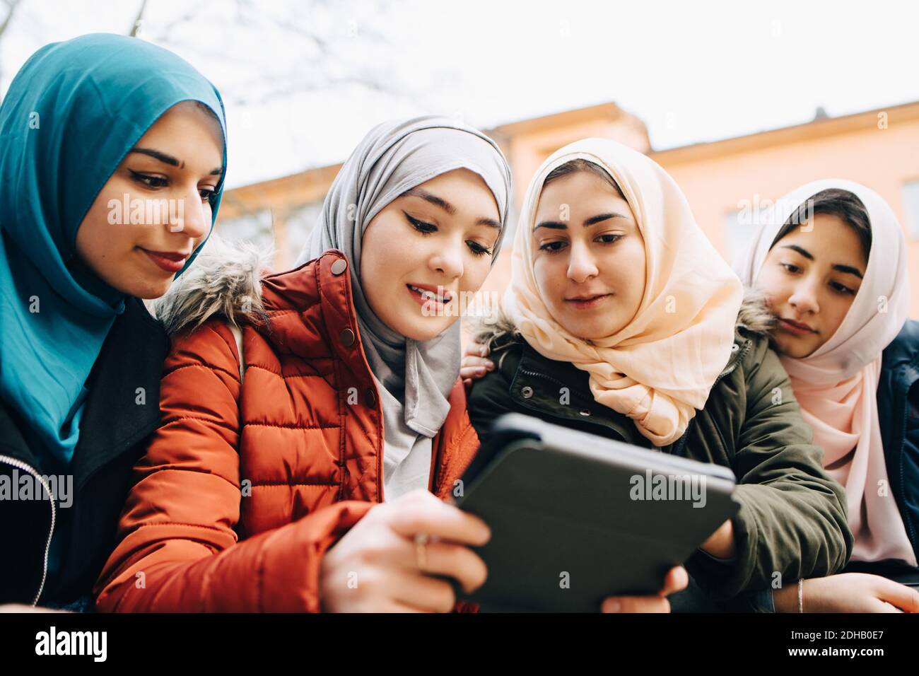 Vue sous angle d'amis musulmans multiethniques partageant une tablette numérique Banque D'Images