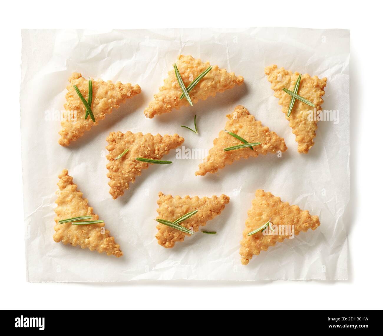 biscuits au fromage fraîchement cuits, décorés de romarin sur une feuille de papier à pâtisserie isolée sur fond blanc, vue du dessus Banque D'Images
