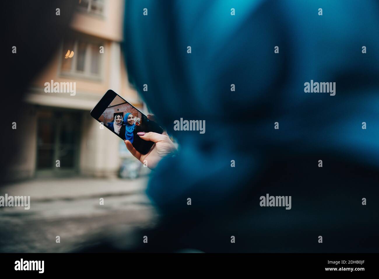 Image rognée d'une femme prenant un selfie avec un ami en ville Banque D'Images