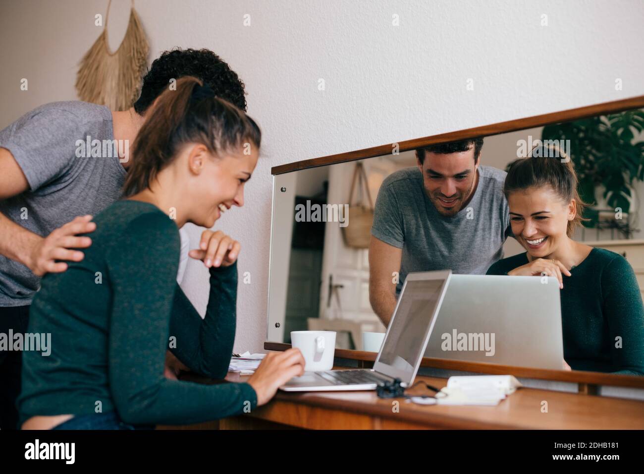 Petit ami et petite amie souriant tout en regardant un ordinateur portable dans la chambre Banque D'Images