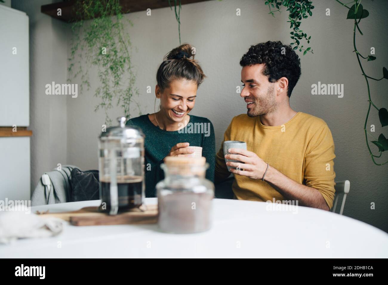 Petit ami souriant et petite amie prenant un café à table dans la vie chambre Banque D'Images