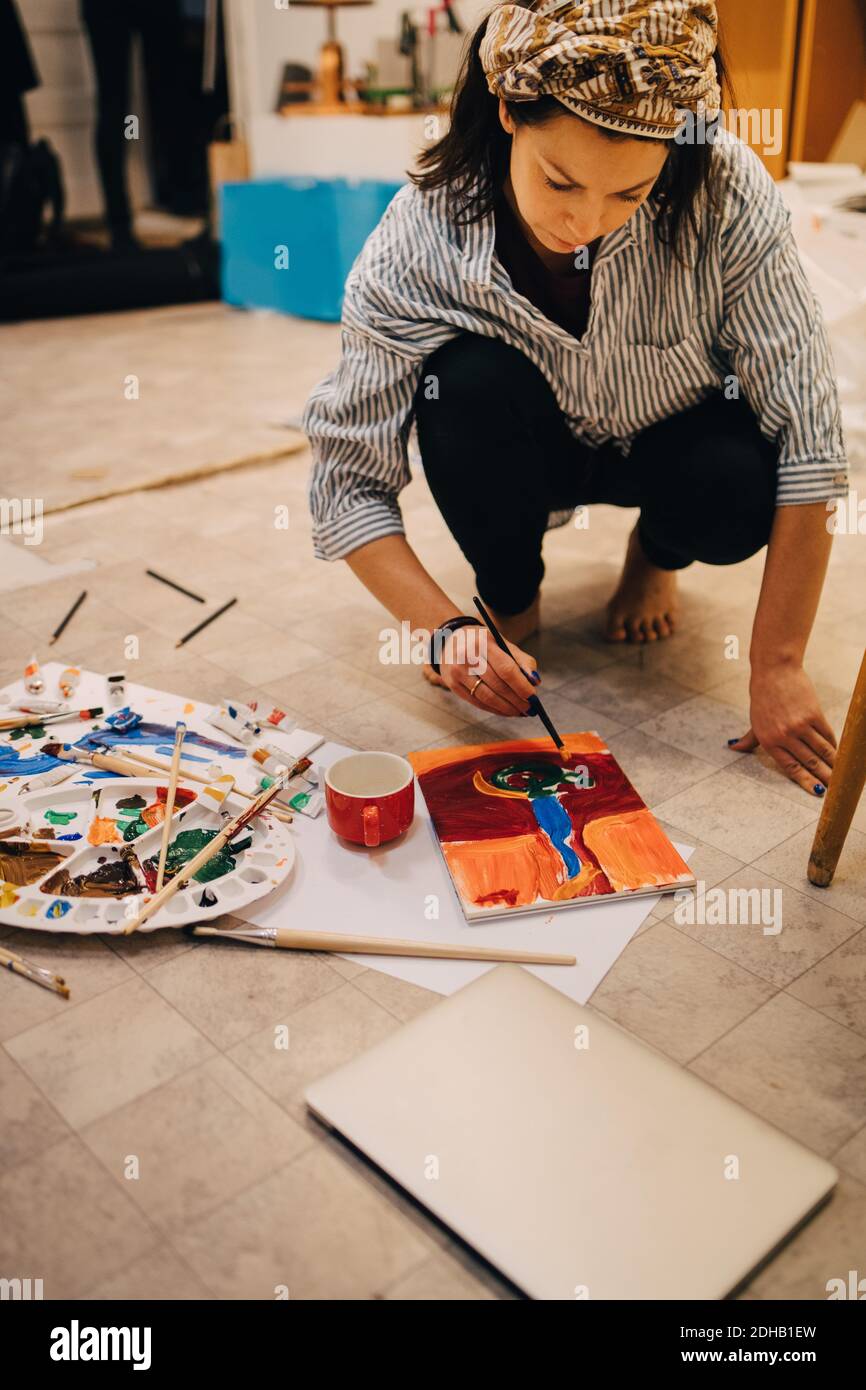 Une artiste féminine peint sur papier tout en se croquant au studio d'art Banque D'Images
