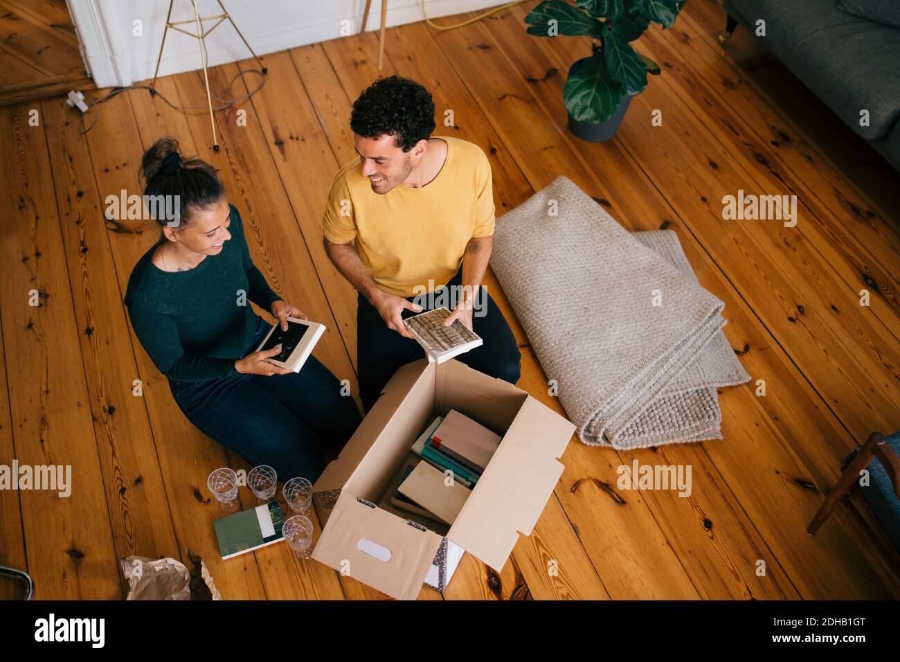 Couple souriant en train de retirer des romans de la boîte dans le salon à nouvelle maison Banque D'Images