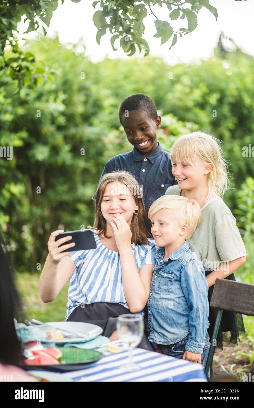 Fille prenant selfie avec des amis sur le téléphone mobile dans l'arrière-cour Banque D'Images