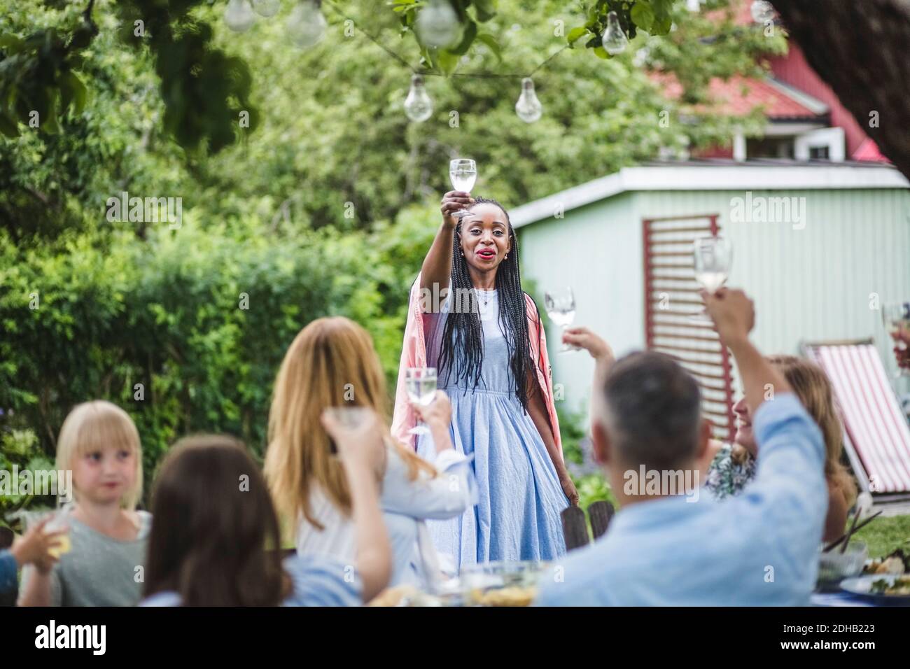 Femme souriante qui toasque avec ses amis et sa famille dans l'arrière-cour pendant la fête du week-end Banque D'Images