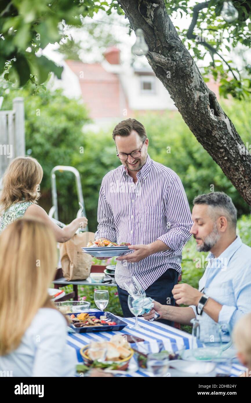 Des amis matures appréciant et partageant de la nourriture à table le week-end fête Banque D'Images