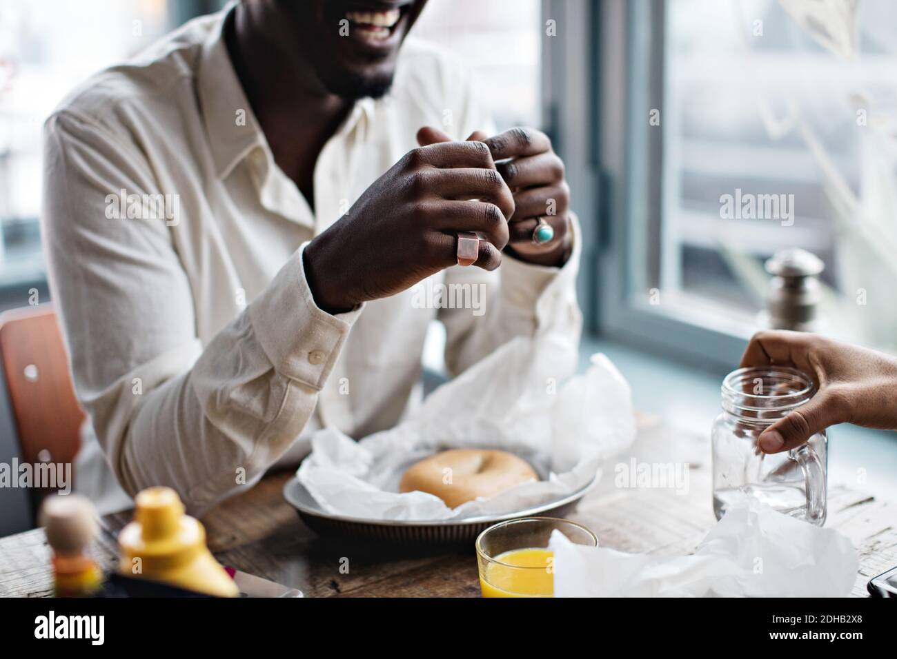 Mi-section de l'homme avec un ami prenant un brunch à la table restaurant Banque D'Images