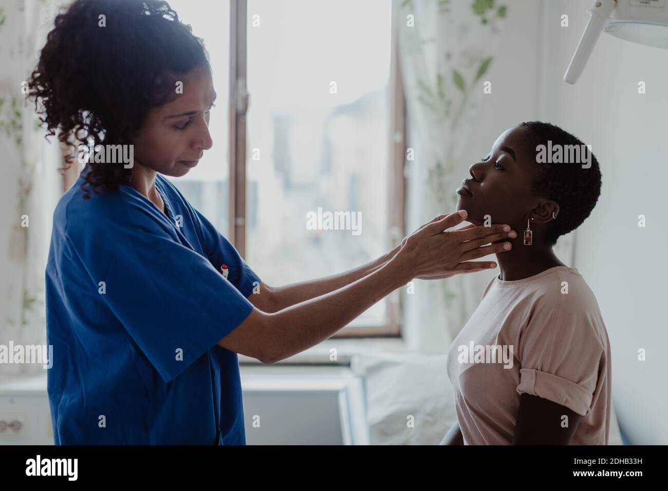 Infirmière féminine examinant la gorge d'un jeune patient à l'hôpital Banque D'Images