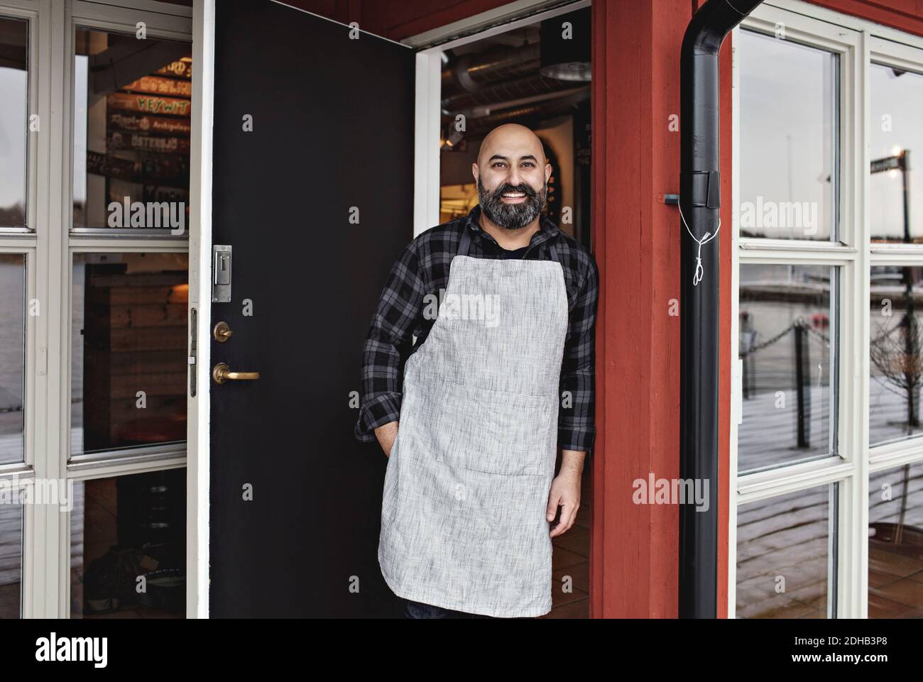Portrait d'un travailleur souriant debout à la porte du restaurant Banque D'Images