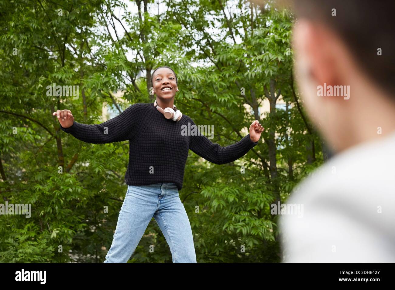 Une adolescente souriante avec des bras surchargés dansant au parc Banque D'Images