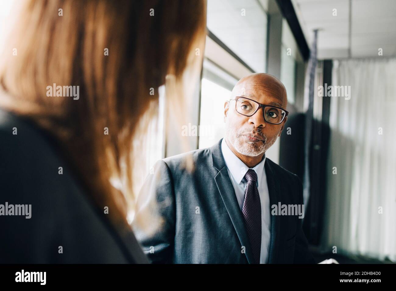 Cadre supérieur regardant une collègue de travail pendant qu'elle est au conseil d'administration chambre au bureau Banque D'Images