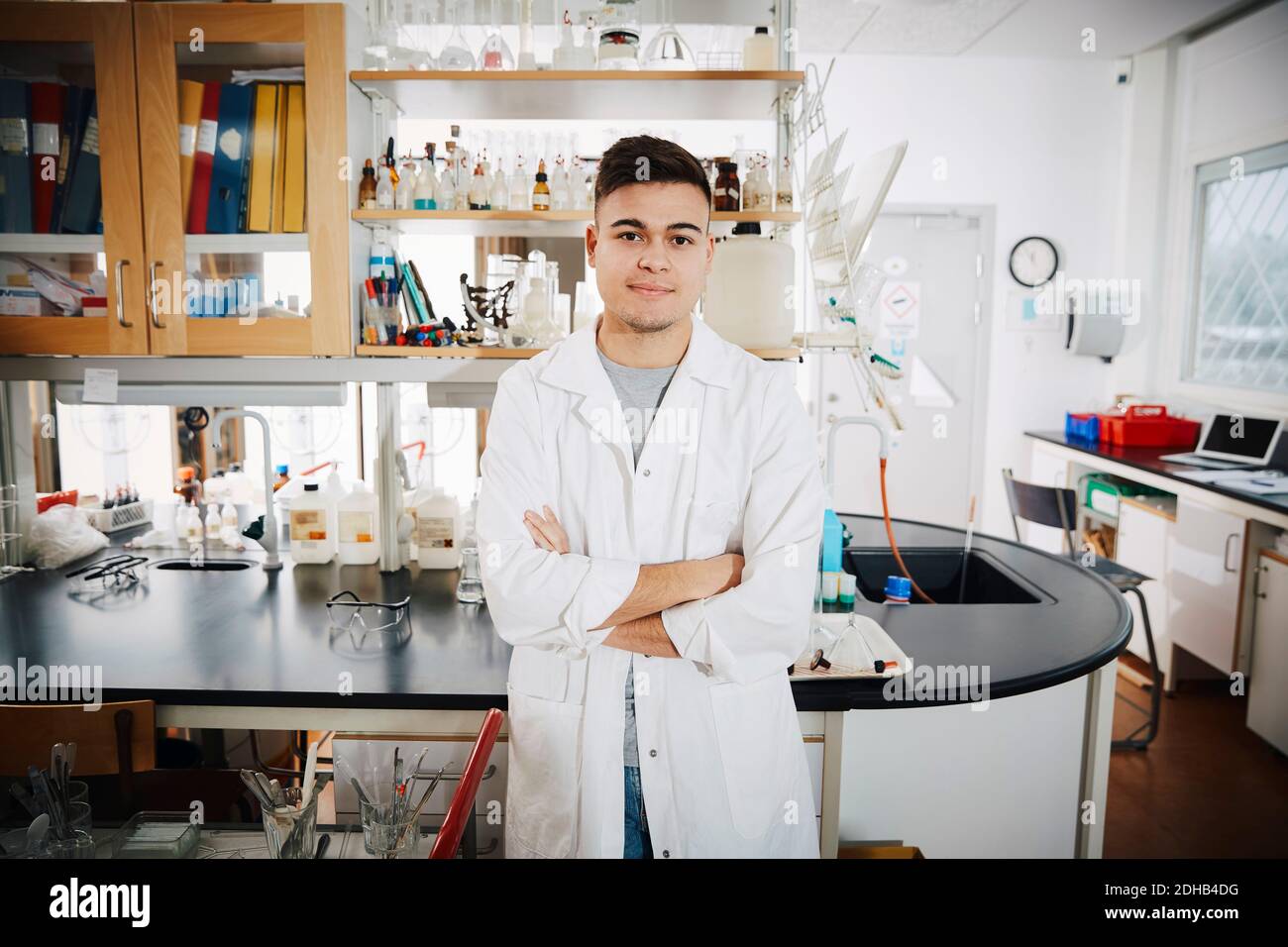 Portrait d'un jeune homme confiant étudiant à l'université debout avec les bras croisé en laboratoire de chimie Banque D'Images