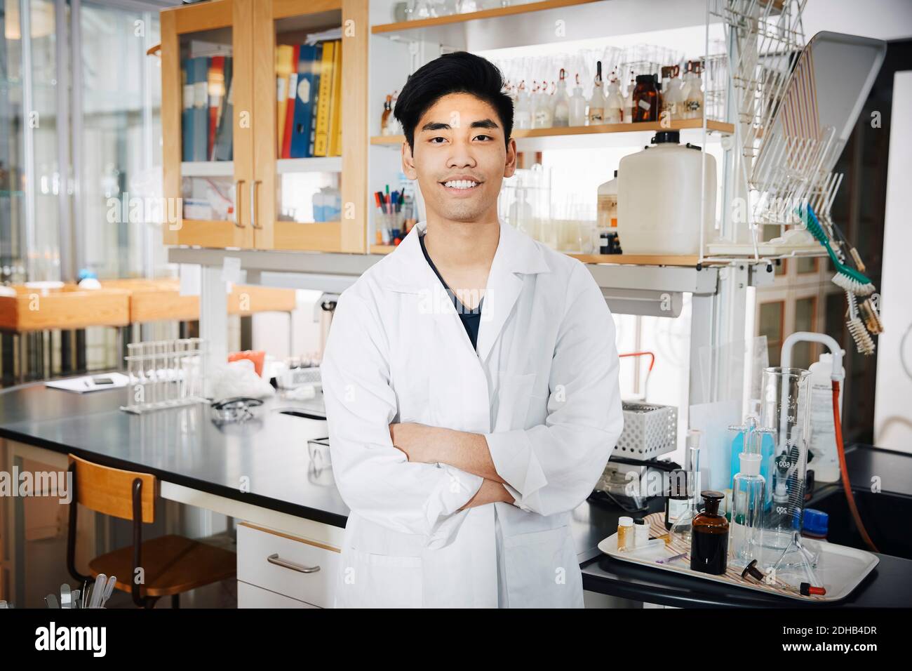 Portrait d'un jeune homme confiant étudiant à l'université debout avec les bras croisé au laboratoire de chimie Banque D'Images