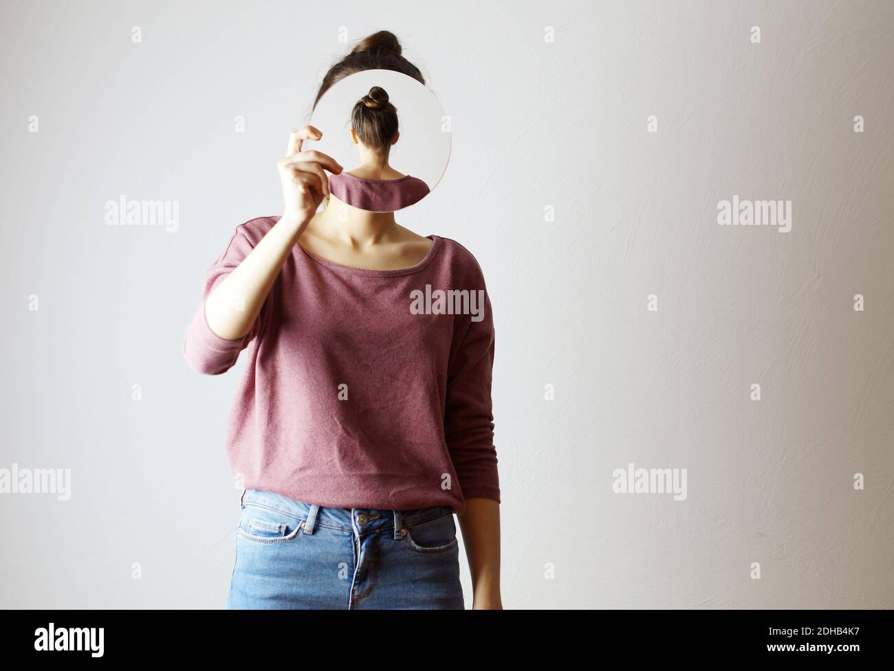 Qui suis-je ? femme tenant un miroir devant son visage. Sans visage, identité non reconnaissable, le miroir montre son dos. Cacher son visage Banque D'Images