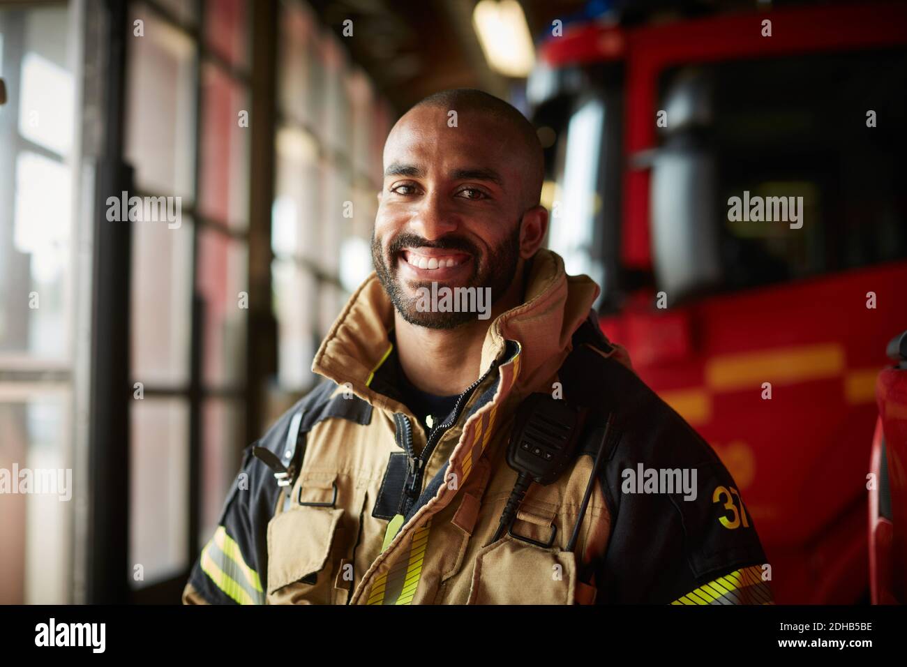 Portrait d'un pompier masculin souriant en uniforme à la caserne de pompiers Banque D'Images