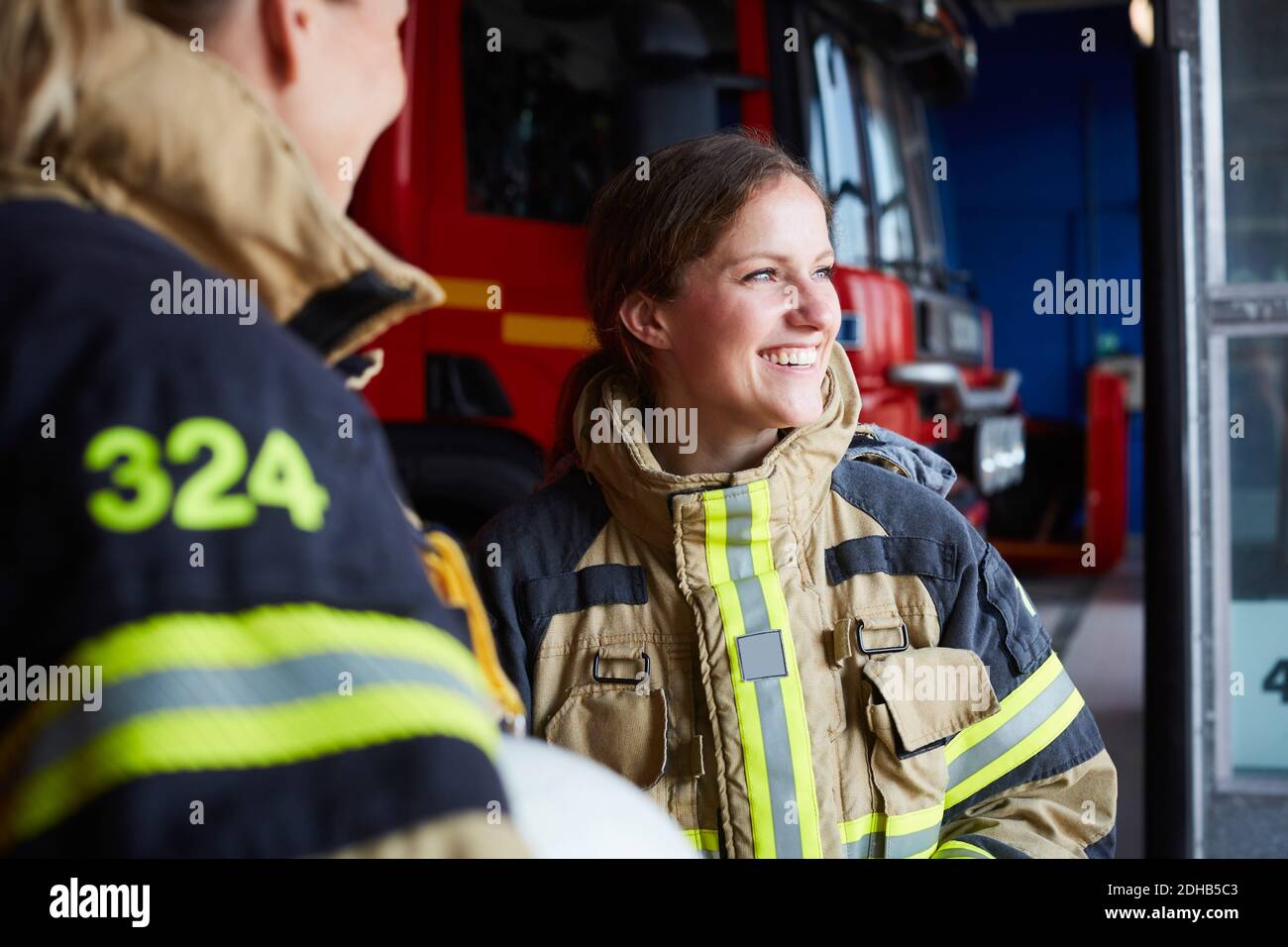 Femme souriante pompier debout avec un collègue dans la caserne de pompiers Banque D'Images