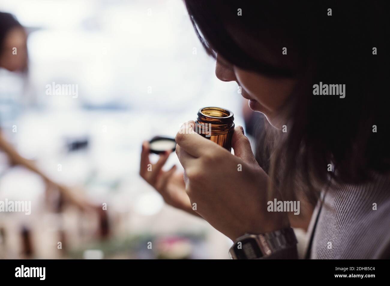 Jeune femme sentant le parfum de la bouteille à l'atelier Banque D'Images