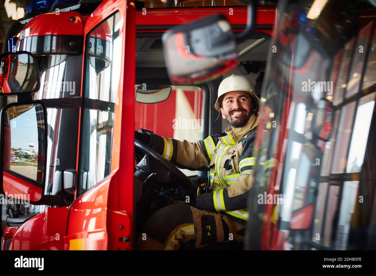 Pompier regardant loin en étant assis dans un camion de pompiers au feu station Banque D'Images