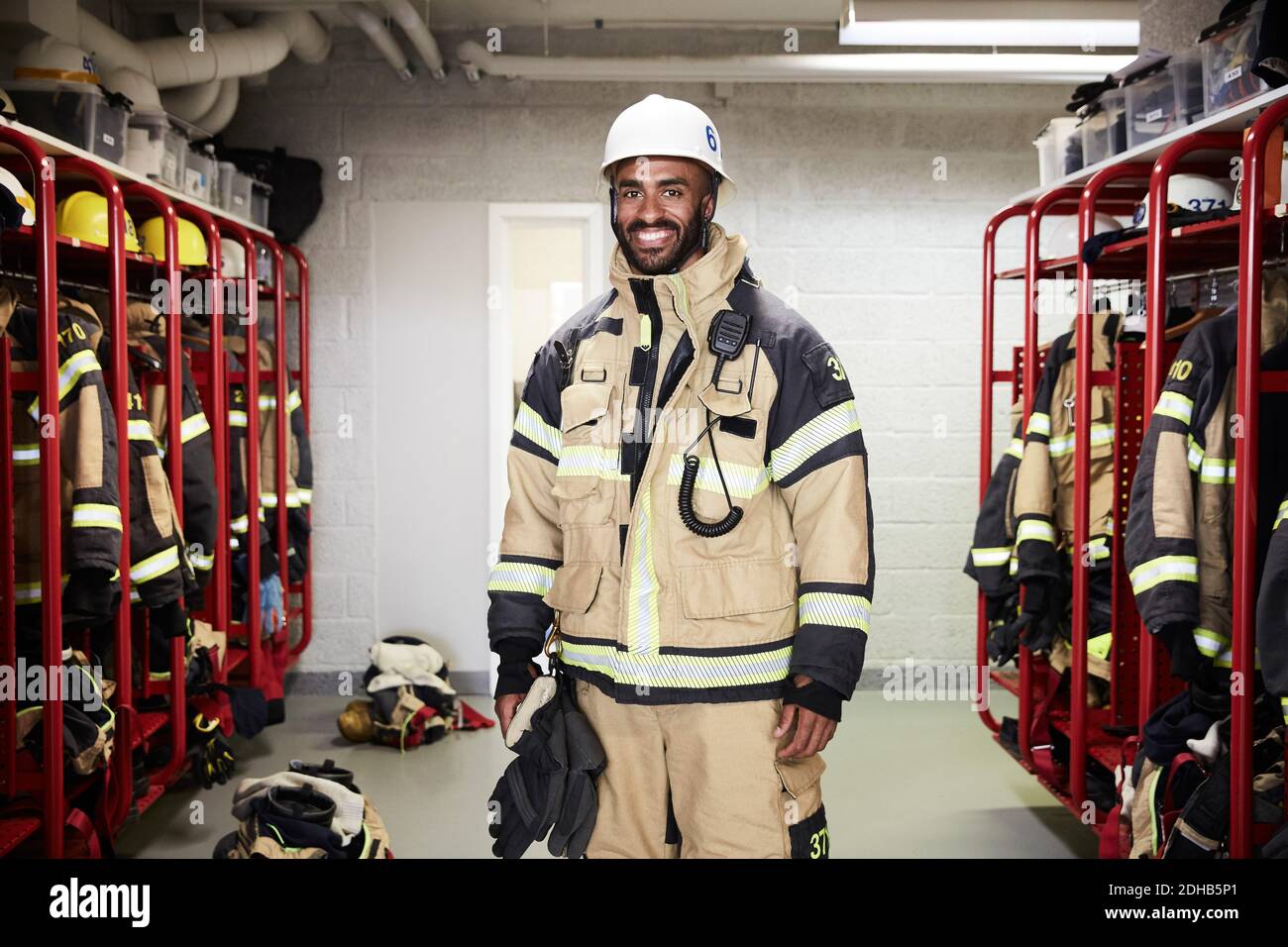 Portrait d'un pompier masculin souriant dans le vestiaire au feu station Banque D'Images