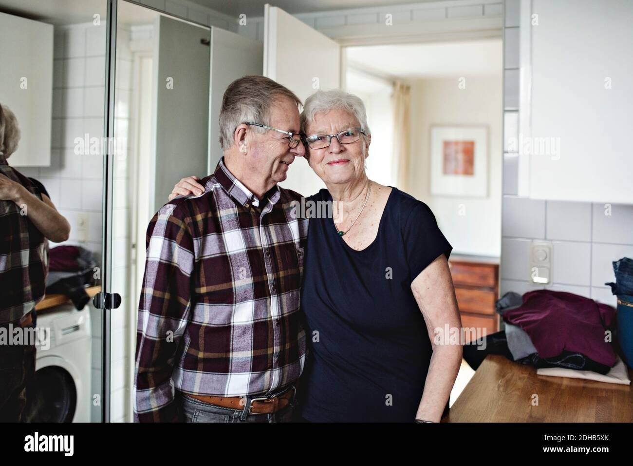 Portrait d'une femme âgée souriante debout avec un homme dans la salle de bains à la maison Banque D'Images