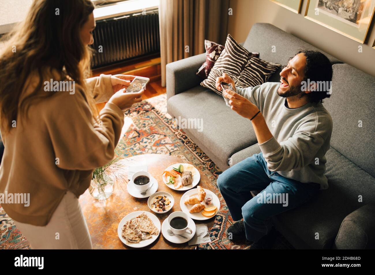 Couple prenant le petit déjeuner avec un smartphone dans la chambre d'hôtel Banque D'Images