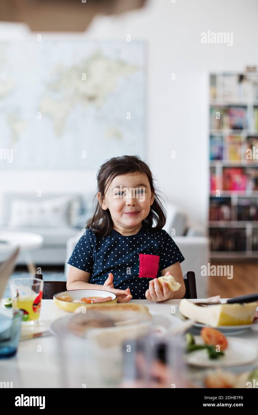Portrait d'une jolie fille souriante prenant le petit déjeuner à la table maison Banque D'Images