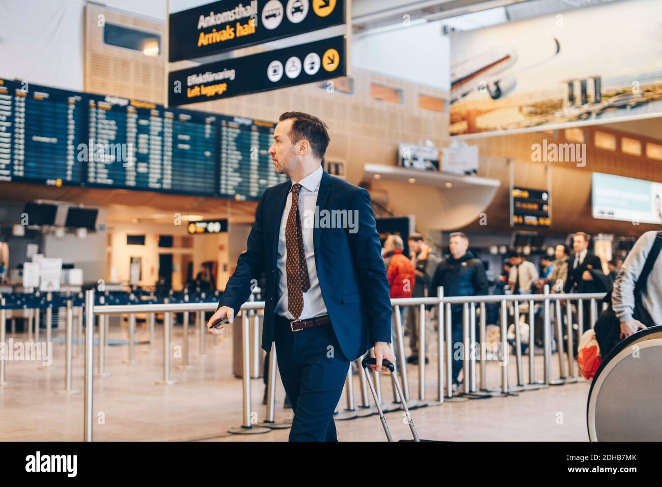 Homme d'affaires mature avec bagages à pied dans le terminal de l'aéroport Banque D'Images