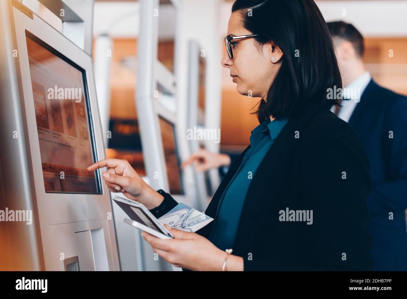 Vue latérale d'une femme d'affaires de taille moyenne adulte utilisant la machine d'enregistrement à l'aéroport Banque D'Images