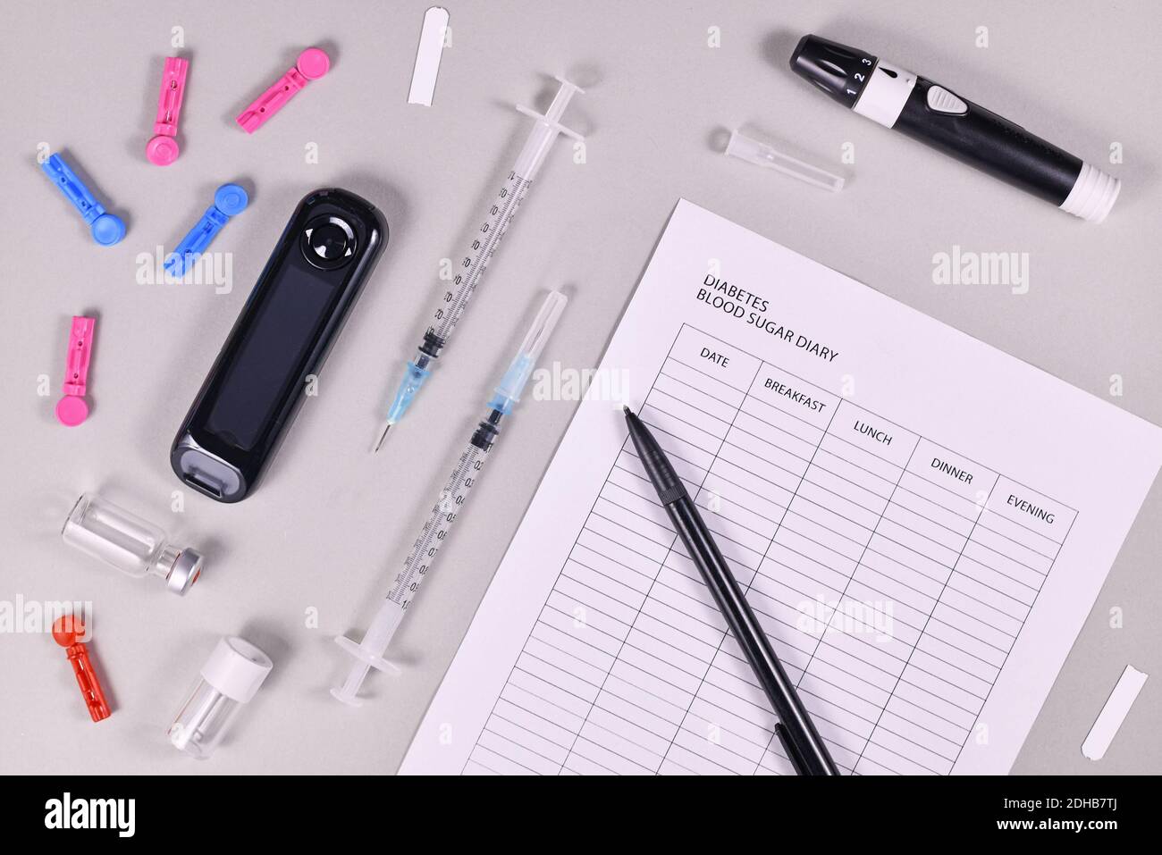 Journal de glycémie pour le diabète avec glucomètre, lancettes, bandes de tests et dispositif de lancing sur fond gris Banque D'Images
