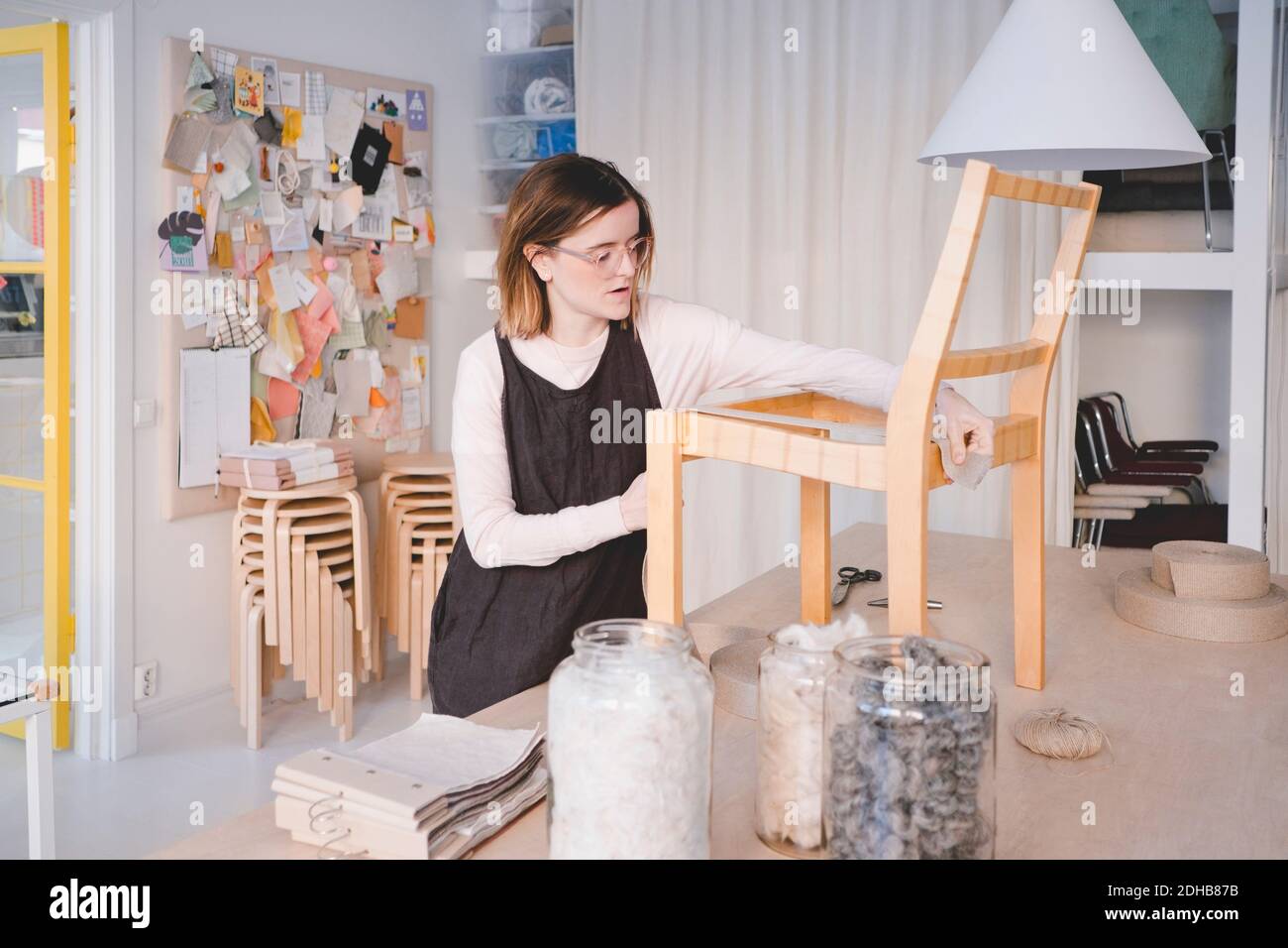 Jeune femme femme de sellerie travaillant sur la chaise dans l'atelier Banque D'Images