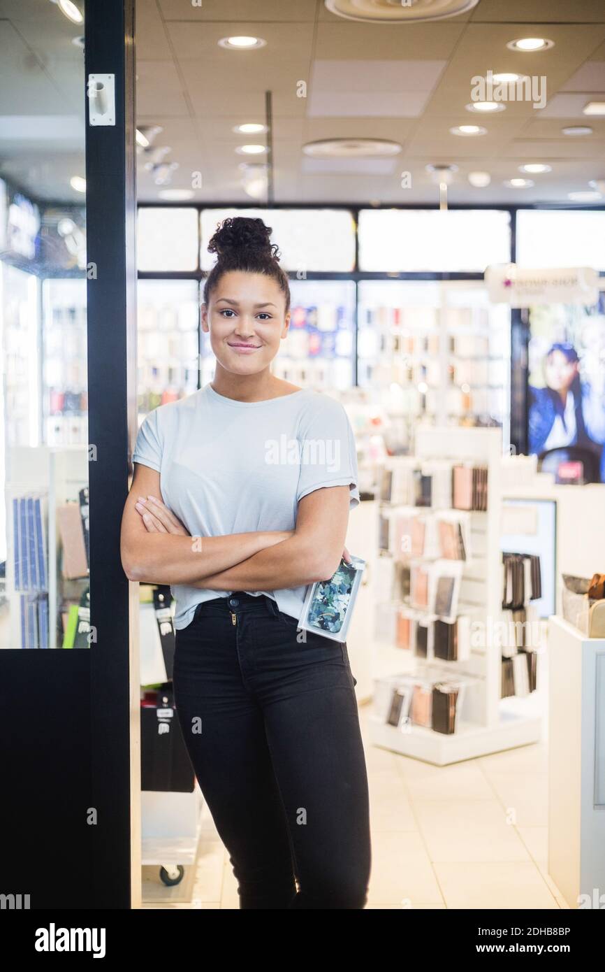 Portrait d'une jeune femme de vente souriante debout avec couvercle de téléphone à l'entrée du magasin Banque D'Images