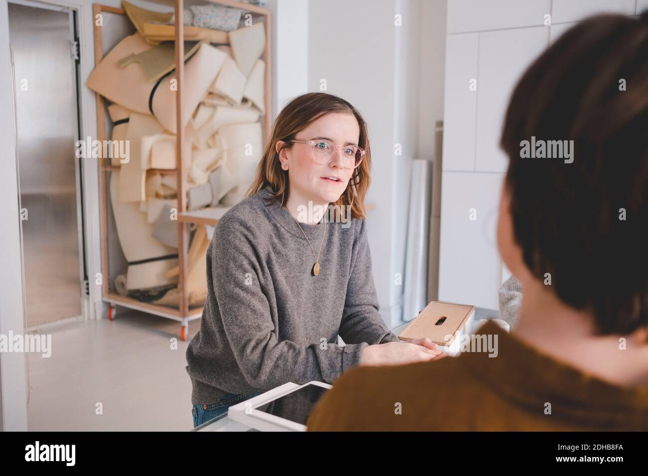 Une jeune femme entrepreneure discute avec un collègue dans un atelier de sellerie Banque D'Images