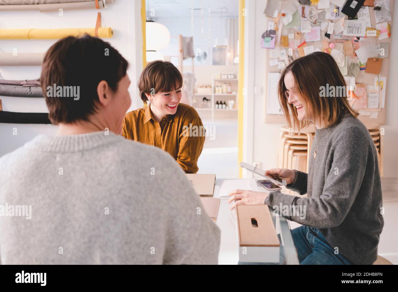 Un designer d'intérieur souriant discute avec des collègues à la réception dans l'atelier Banque D'Images
