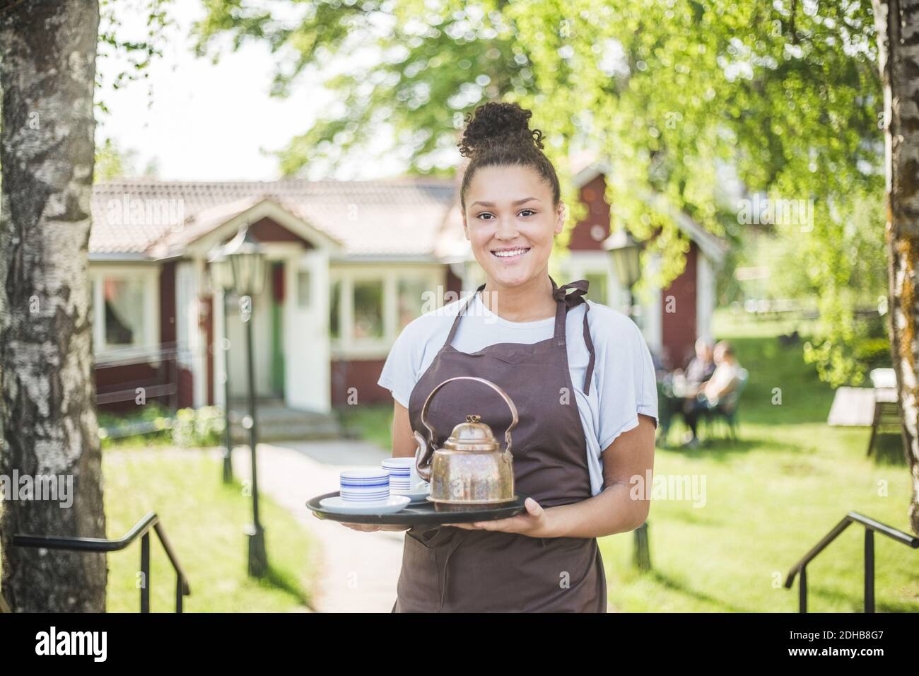 Portrait d'une jeune serveuse souriante tenant un plateau de service au restaurant Banque D'Images Portrait d'une jeune serveuse souriante tenant un plateau de service au restaurant Banque D'Images