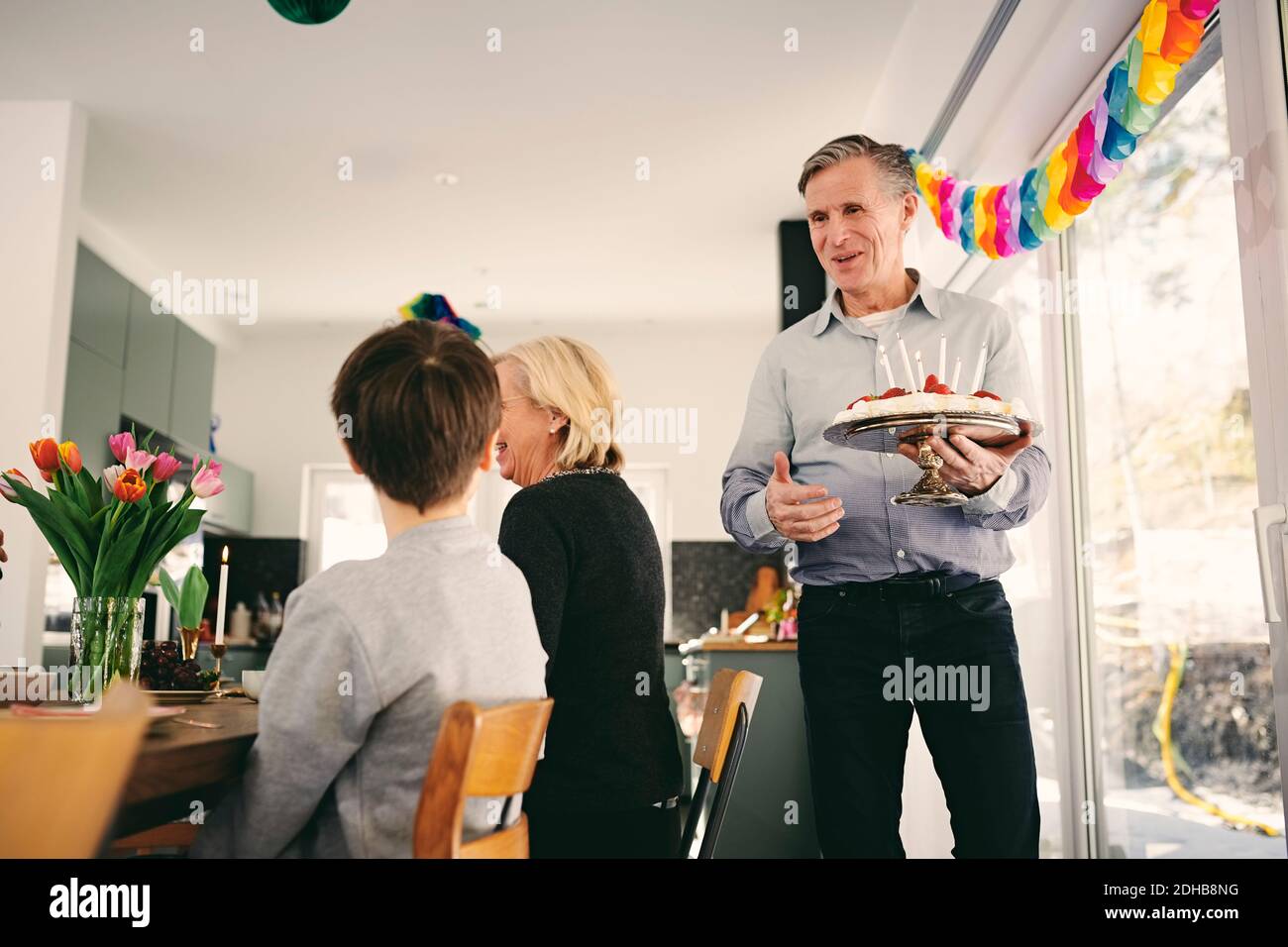 Garçon regardant un grand-père tenant un gâteau d'anniversaire en fête Banque D'Images