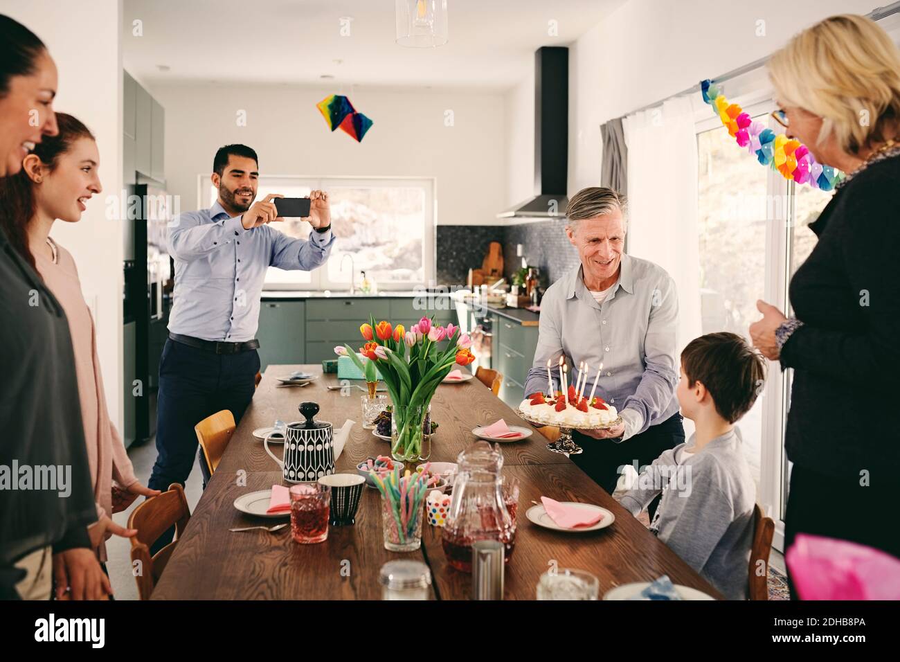 Homme photographiant garçon avec famille pendant la fête d'anniversaire par SMART téléphone Banque D'Images