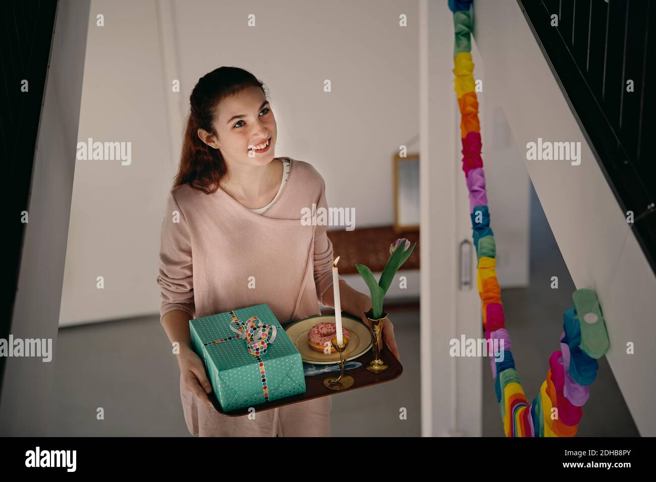 Vue en grand angle d'une fille souriante portant un cadeau d'anniversaire en marchant sur les marches Banque D'Images