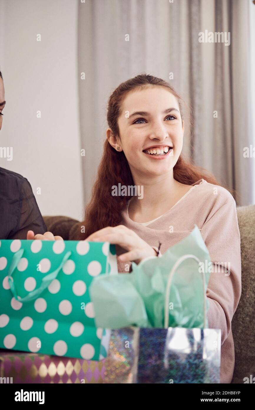 Une fille souriante regarde loin tout en tenant un cadeau d'anniversaire à la maison Banque D'Images