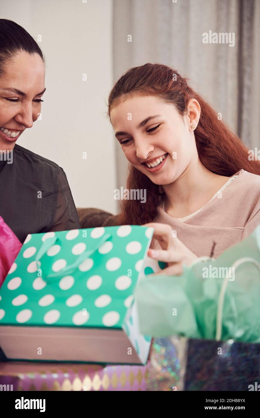 Fille excitée regardant le cadeau d'anniversaire tout en étant assise avec la mère à la maison Banque D'Images