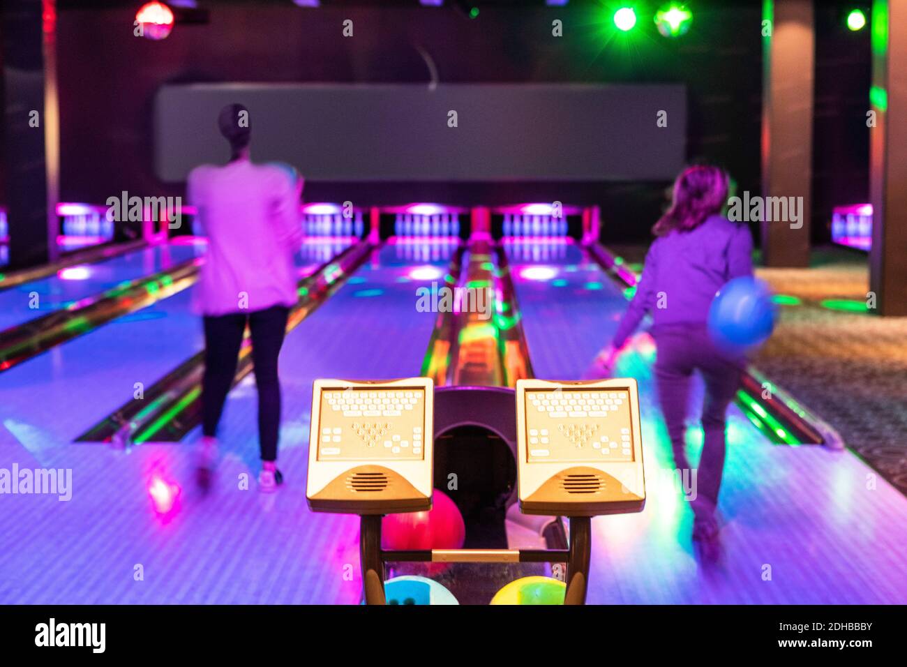 Des moniteurs informatiques contre les adolescentes qui lancent des balles sur le parquet au bowling Banque D'Images