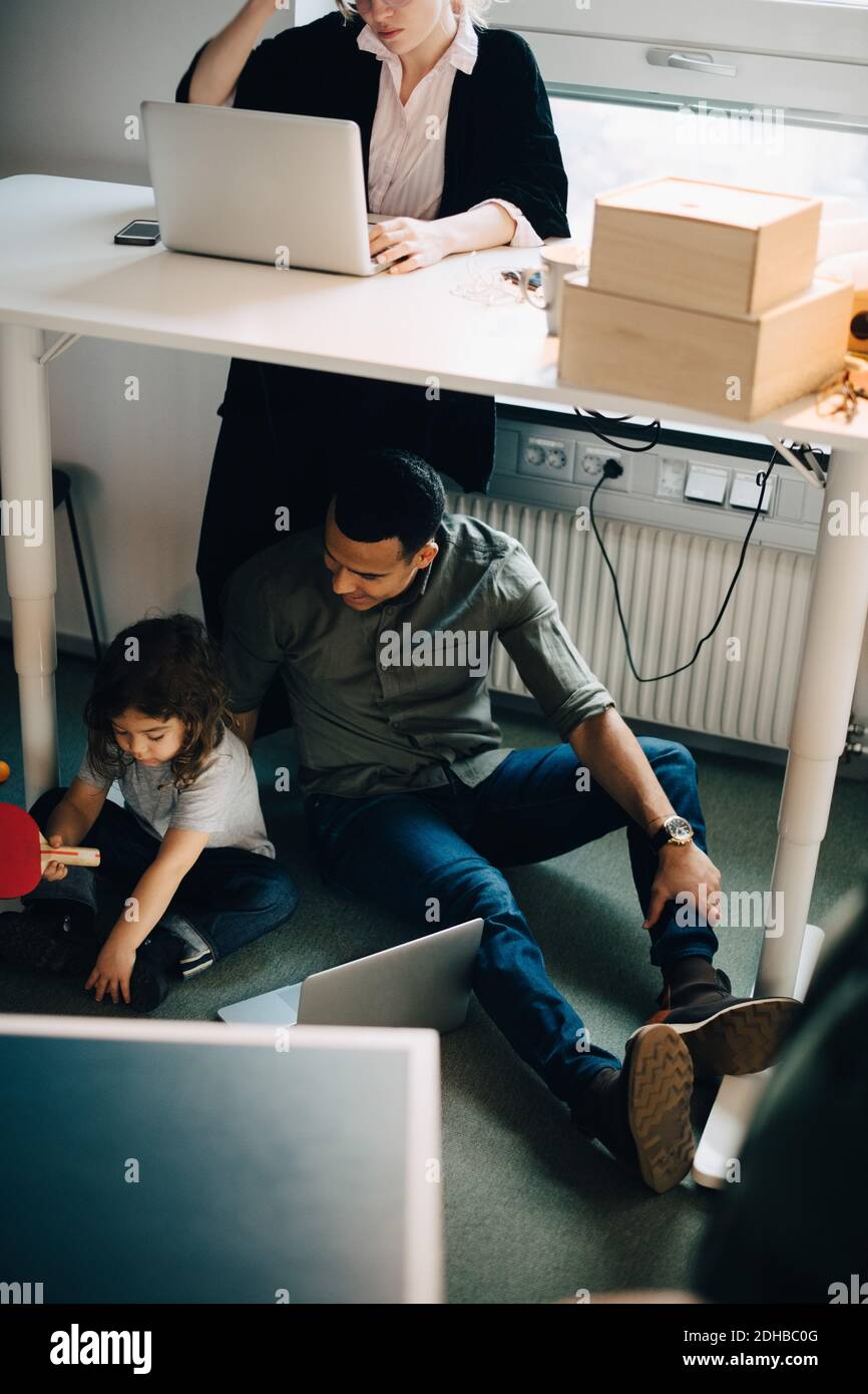 Vue en grand angle du père et du fils assis avec un ordinateur portable par une femme d'affaires travaillant dans un bureau créatif Banque D'Images
