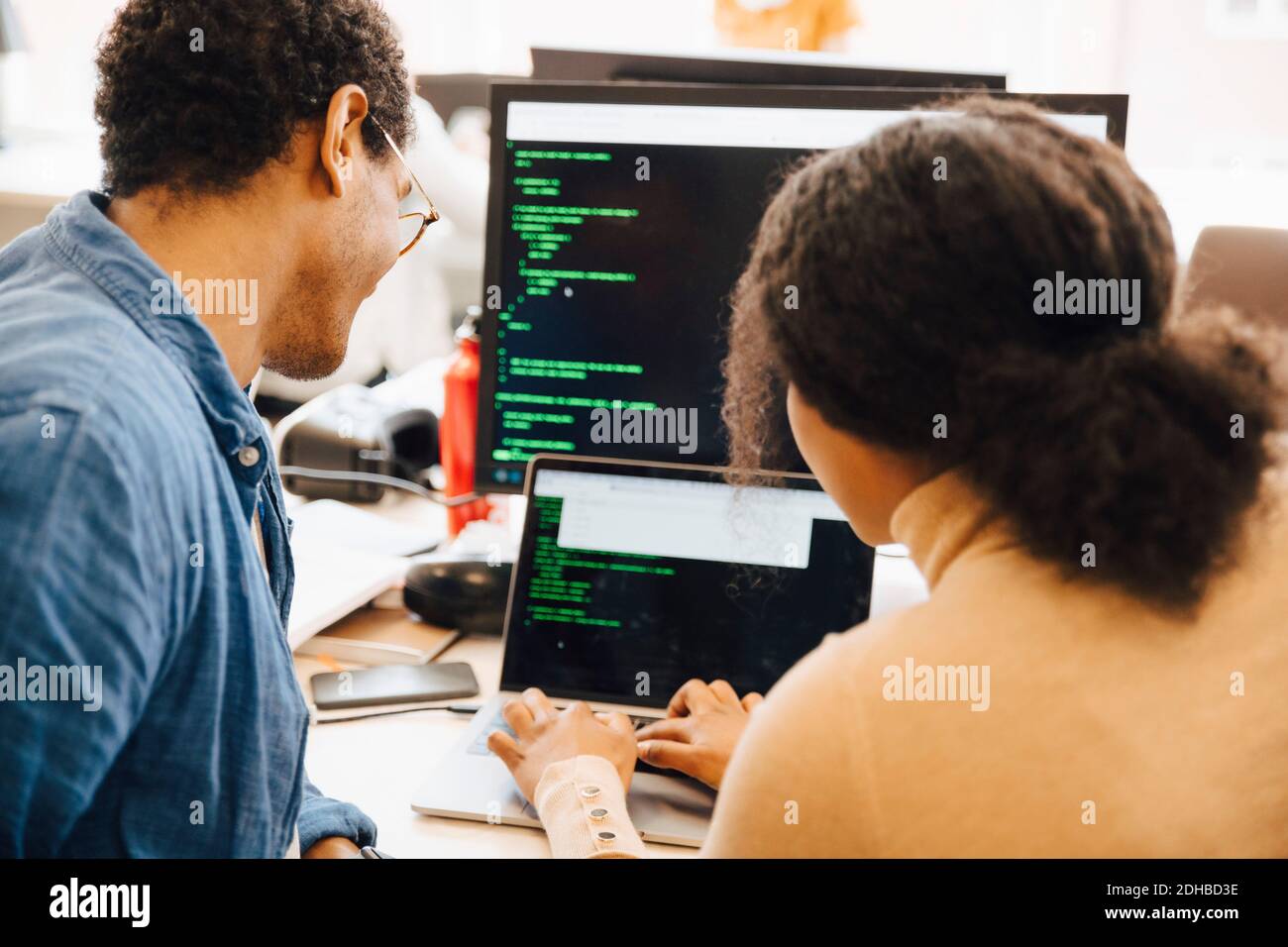 Une hacker informatique explique un collègue sur un ordinateur portable sur le bureau au bureau Banque D'Images