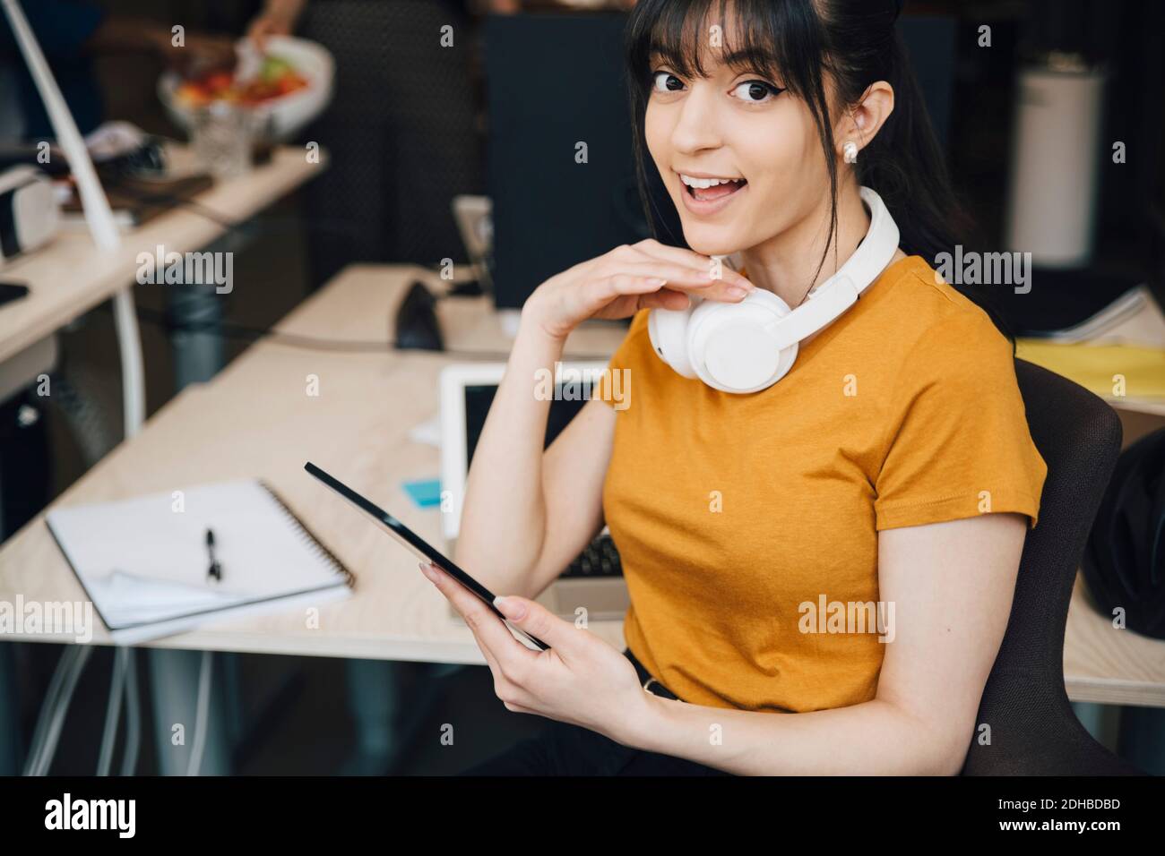 Portrait d'une femme heureuse hacker d'ordinateur à l'aide de la tablette numérique pendant assis au bureau Banque D'Images